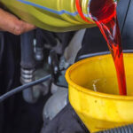 A man pours transmission fluid into his engine