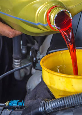 A man pours transmission fluid into his engine